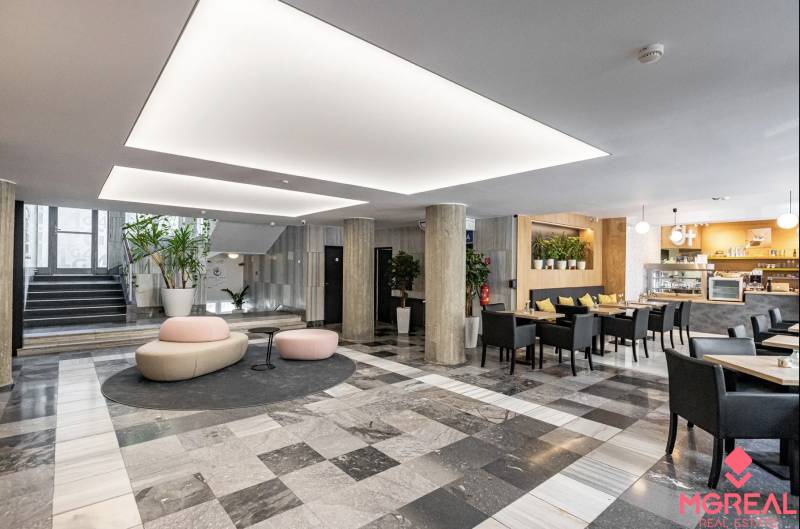 Büros mit schwarz-weißem Boden, Säulen, Sitzgelegenheiten und einem Café im Innenbereich.