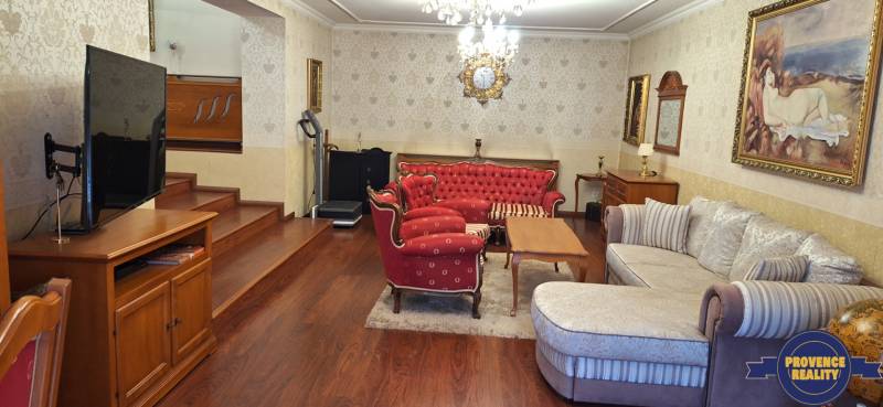 Wohnzimmer in einem Einfamilienhaus mit roten Möbeln und einem Fernseher auf einem Boden mit Holzdekor.