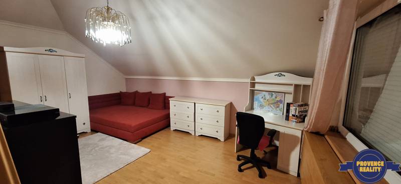 Schlafzimmer mit Möbeln, rotem Sofa, Schreibtisch und Holzboden in einem Einfamilienhaus.