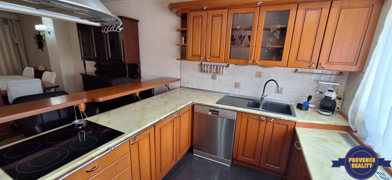 Küche in einem Einfamilienhaus mit Holzschränken und einer Spülmaschine aus Edelstahl.