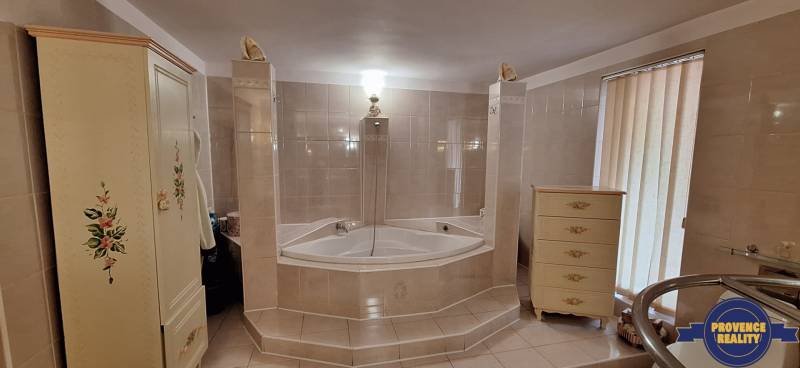 Ein Badezimmer in einem Einfamilienhaus mit einer Eckbadewanne und dekorierten Möbeln.