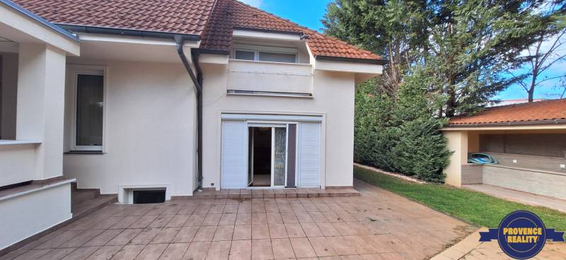 Ein Einfamilienhaus in Komárno mit Terrasse, Garten und weißen Fensterläden.