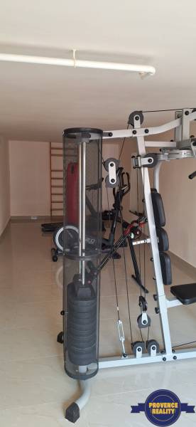 Fitnessraum mit Kraftgeräten im Einfamilienhaus hat eine helle Keramikoberfläche.