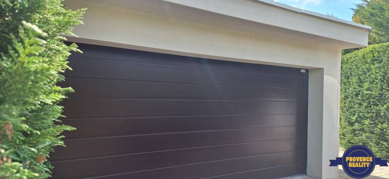 Garagentor bei einem Einfamilienhaus in Komárno, umgeben von Grün.