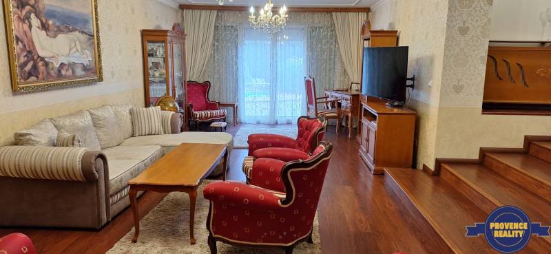 Wohnzimmer in einem Einfamilienhaus mit roten Sesseln und einem Boden in Holzoptik.