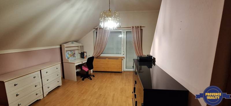 Ein Zimmer mit Holzboden, Möbeln und einem Kronleuchter in einem Einfamilienhaus.