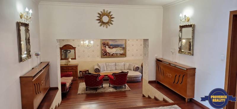 Luxuriöses Interieur eines Einfamilienhauses mit Holzelementen, Sofa und Kunstwerken an den Wänden.