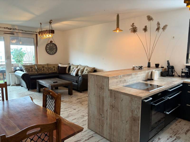 Küche mit Esszimmer in einer 3-Zimmer-Wohnung, Boden mit Holzdekor, komfortables Sofa.