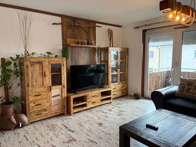 Wohnzimmer in einer 3-Zimmer-Wohnung mit Holzmöbeln und Boden in Holzoptik.