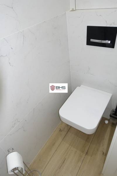 Badezimmer mit Toilette und Holzboden in einer 3-Zimmer-Wohnung.