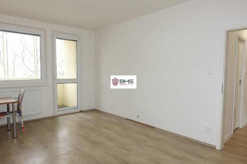 Ein Zimmer mit einem Holzboden in einer 3-Zimmer-Wohnung, Tisch und Stuhl.