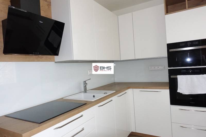 Eine Küche mit weißen Schränken und Geräten, ergänzt durch einen Bodenbelag in Holzoptik in einer 3-Zimmer-Wohnung.