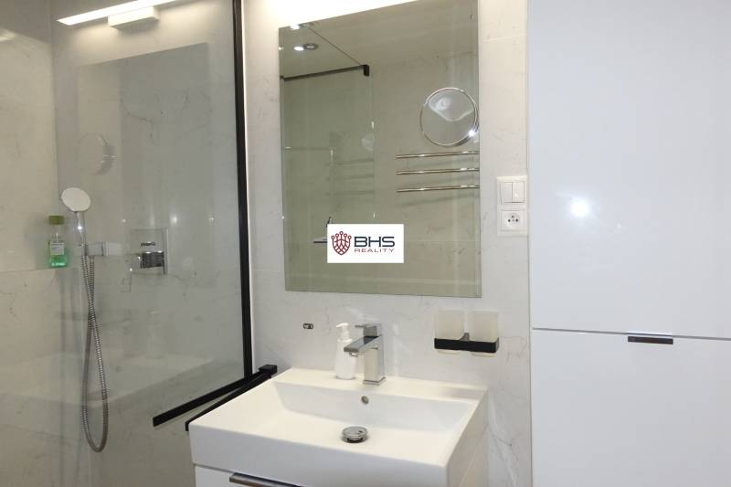 Badezimmer in einer 3-Zimmer-Wohnung mit Waschbecken, Spiegel und Duschkabine.