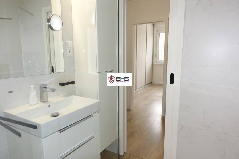 Badezimmer mit Waschbecken, weißem Schrank und Blick auf den Flur in einer 3-Zimmer-Wohnung.