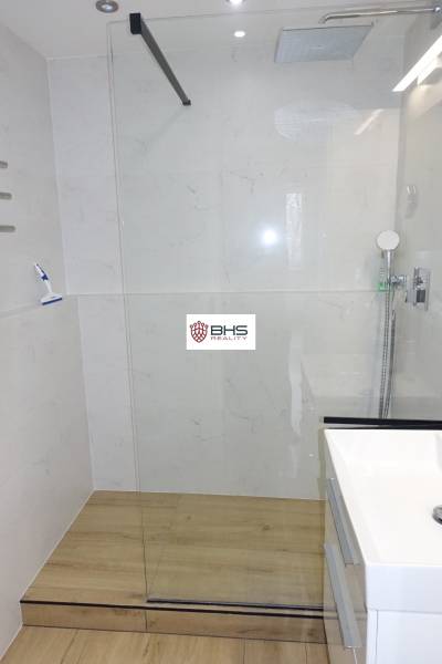 Duschkabine mit Verglasung und Boden in Holzoptik in einer 3-Zimmer-Wohnung.