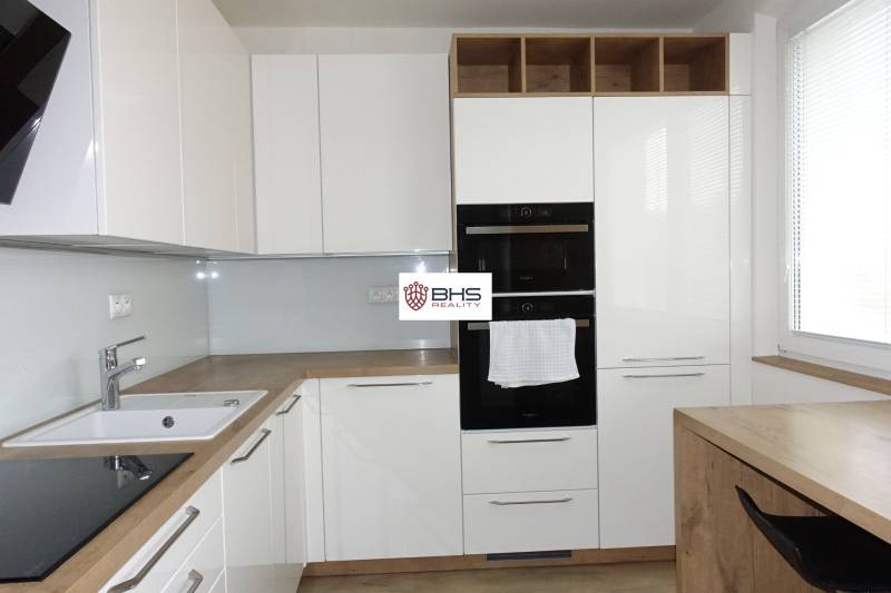 Moderne Küche mit weißen Schränken und Holzboden in einer 3-Zimmer-Wohnung.