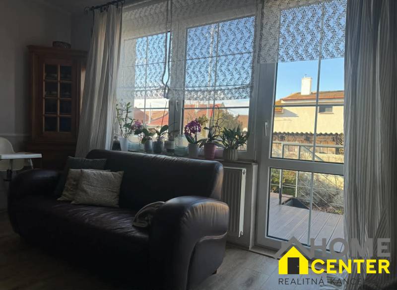 Ledersofa und Fenster mit Spitzenvorhängen in einem Einfamilienhaus mit Holzboden.