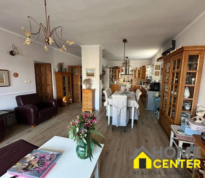 Wohnzimmer mit Küche in einem Einfamilienhaus, Boden mit Holzdekor, Blumen auf dem Tisch.