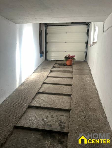 Garage in einem Einfamilienhaus mit Betonrampe und Blumenkasten an der Wand.