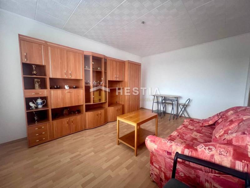 Wohnzimmer in einer 3-Zimmer-Wohnung mit rotem Sofa und Wohnwand aus Holz.