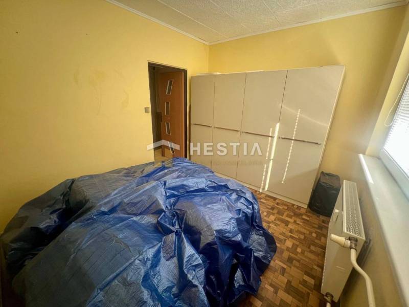 Ein Zimmer mit einem Schrank, einem Heizkörper und abgedeckten Möbeln in einer 3-Zimmer-Wohnung.