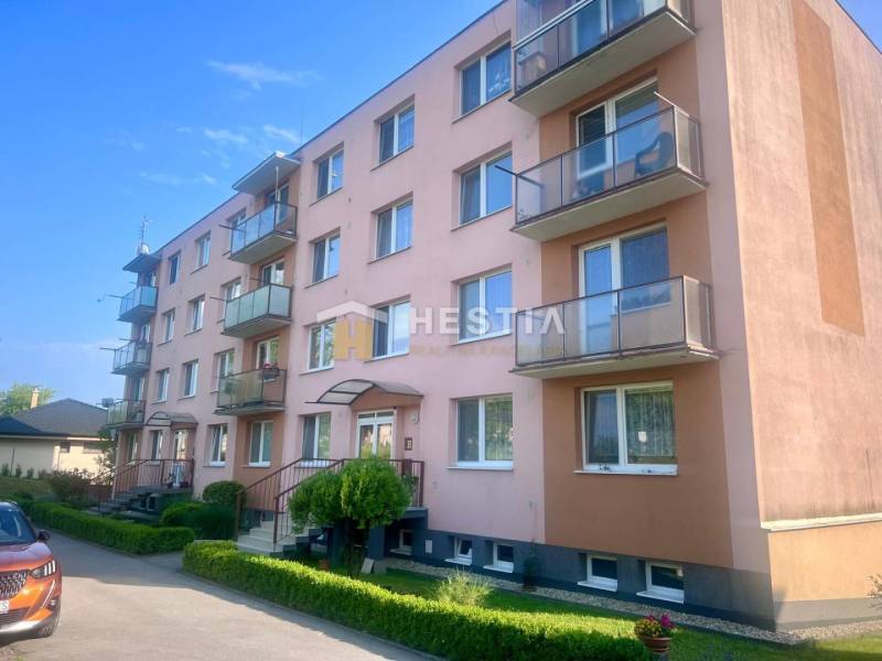 Ein vierstöckiges Wohngebäude in Moravské Lieskové mit Balkonen und Parkmöglichkeiten vor dem Gebäude.