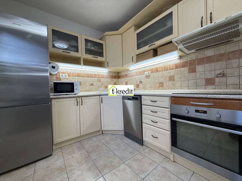 Küche in einer 2-Zimmer-Wohnung mit Geschirrspüler, Backofen, Mikrowelle und Fliesenverkleidung.