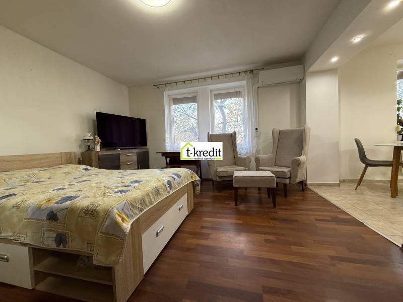 Schlafzimmer in einer 2-Zimmer-Wohnung mit Holzboden und bequemen Sesseln.