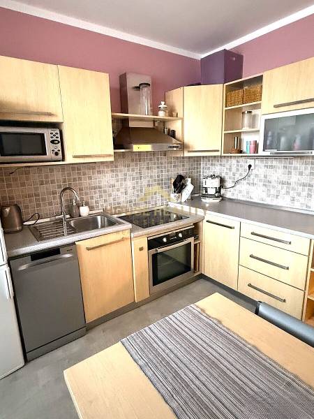 Küche in einer 3-Zimmer-Wohnung mit Holzdekor-Schränken, Trockner und Ofen.