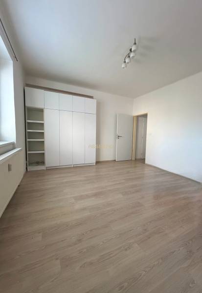 Helles Zimmer mit weißem Schrank und Holzboden in einer Einzimmerwohnung.