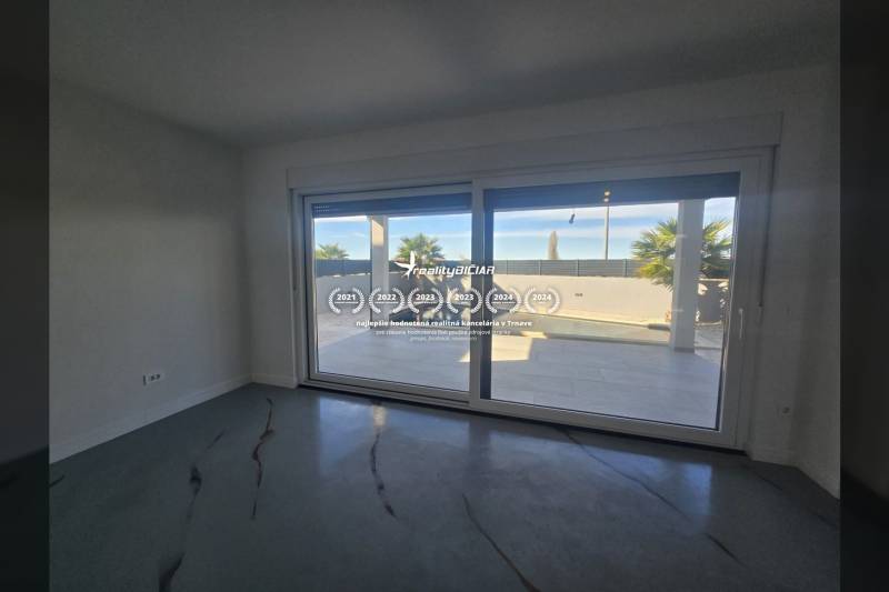 Innenraum der Villa mit großen Verglasungen und Blick auf den Außenbereich mit Pool.