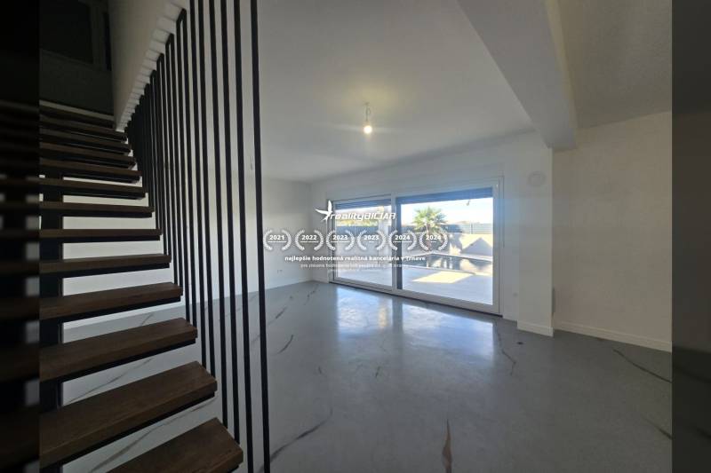 Wohnzimmer in einer Villa mit modernen Treppen und großen Fenstern.