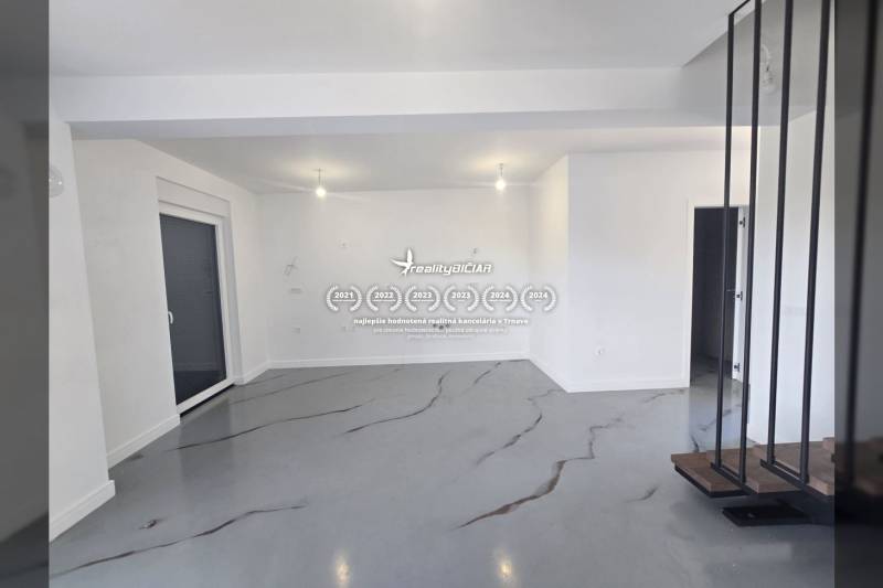 Ein geräumiger Raum in der Villa mit weißen Wänden und einem grauen Boden mit Dekor.