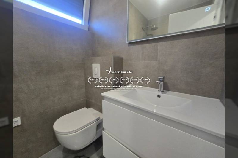 Badezimmer in der Villa mit Waschbecken, hängender Toilette und großem Spiegel.