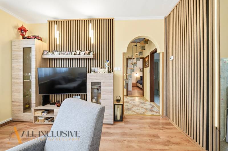 Wohnzimmer in einem Einfamilienhaus mit Fernseher und Boden in Holzoptik.