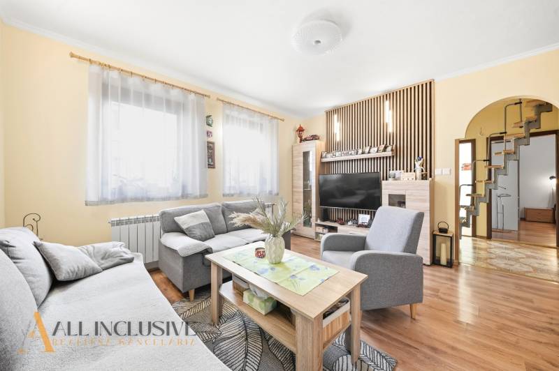 Wohnzimmer in einem Einfamilienhaus mit Sofa, Tisch, Fernseher und Holzboden.