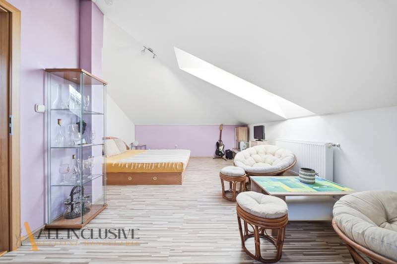 Dachzimmer in einem Einfamilienhaus mit Holzboden, Möbeln und Dachfenstern.