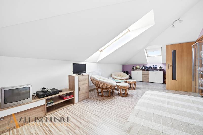 Ein Dachzimmer in einem Einfamilienhaus mit Sesseln und einem Boden in Holzoptik.