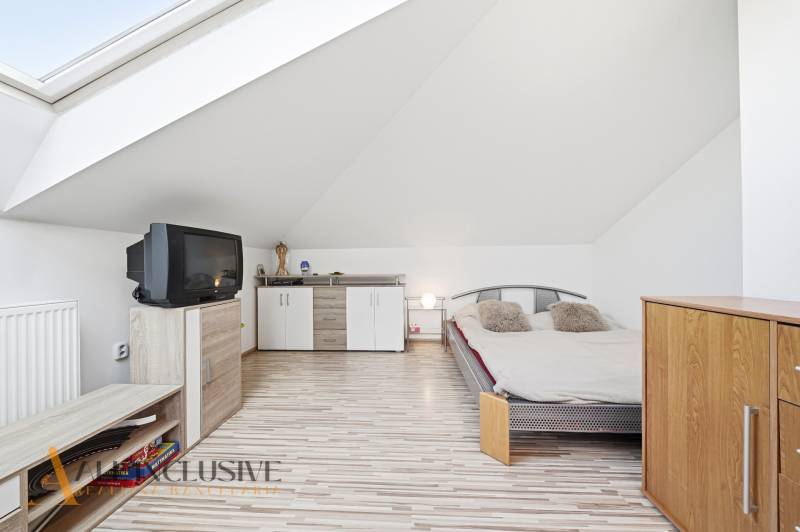 Dachbodenschlafzimmer mit Fernseher, Bett und Schränken in einem Einfamilienhaus.