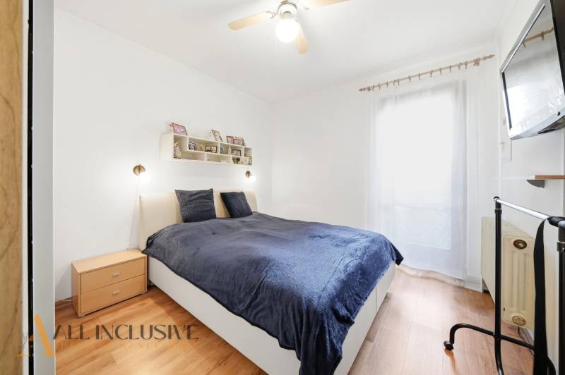 Ein Schlafzimmer in einem Einfamilienhaus mit einem Bett, Holzboden-Dekor und einem Fernseher an der Wand.