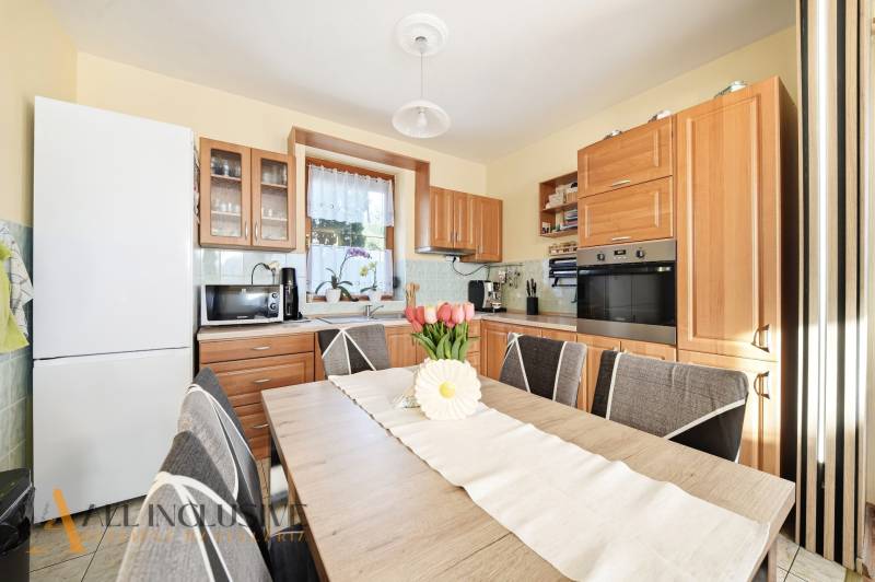 Küche in einem Einfamilienhaus mit Holzmöbeldekor und Ausstattung, Blumendekoration auf dem Tisch.