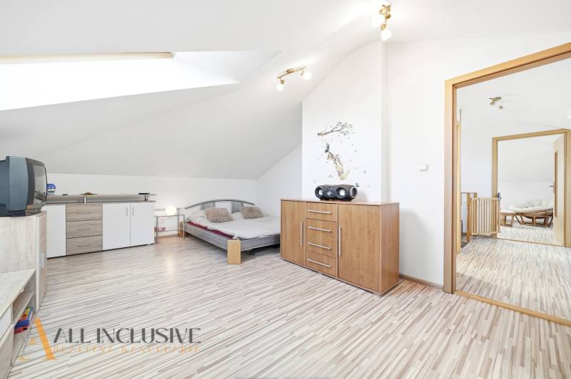 Helles Schlafzimmer mit Holzboden, Kommode und Bett in einem Einfamilienhaus.