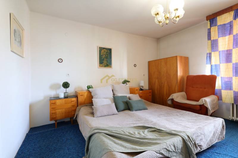 Schlafzimmer mit großem Bett, Holzschränken und Sessel in einem Einfamilienhaus.