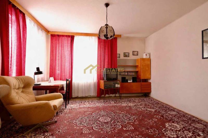 Wohnzimmer in einem Einfamilienhaus mit rotem Teppich, Sessel und Vorhängen an den Fenstern.