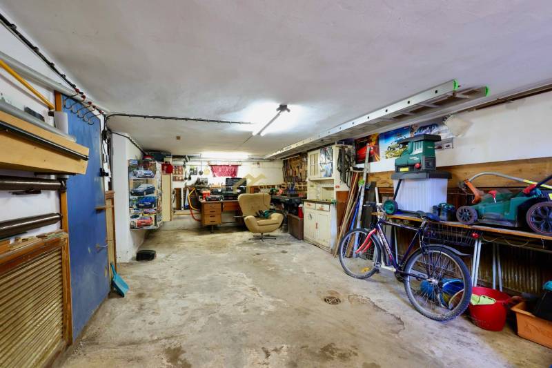 Garage in einem Einfamilienhaus mit Werkzeug, Fahrrad und Arbeitstisch.