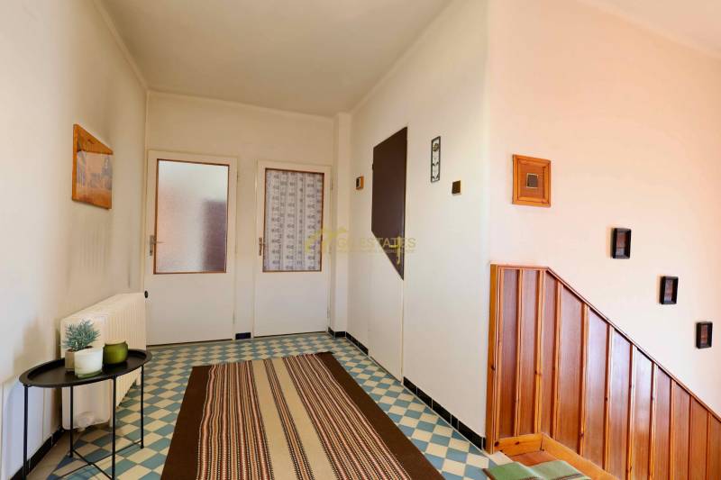 Ein Einfamilienhaus mit gemusterten Fliesen, Holztreppen und einfacher Wanddekoration.