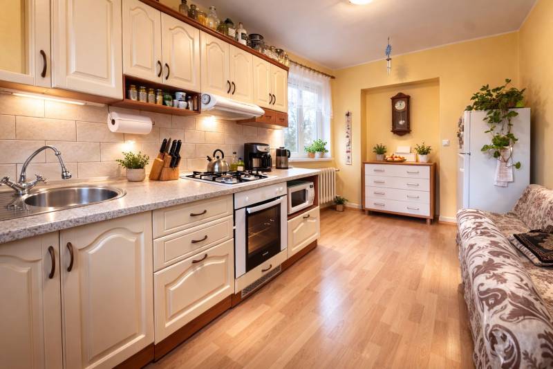 Küche in einer 2-Zimmer-Wohnung mit Holzboden, heller Küchenzeile und Pflanzen.