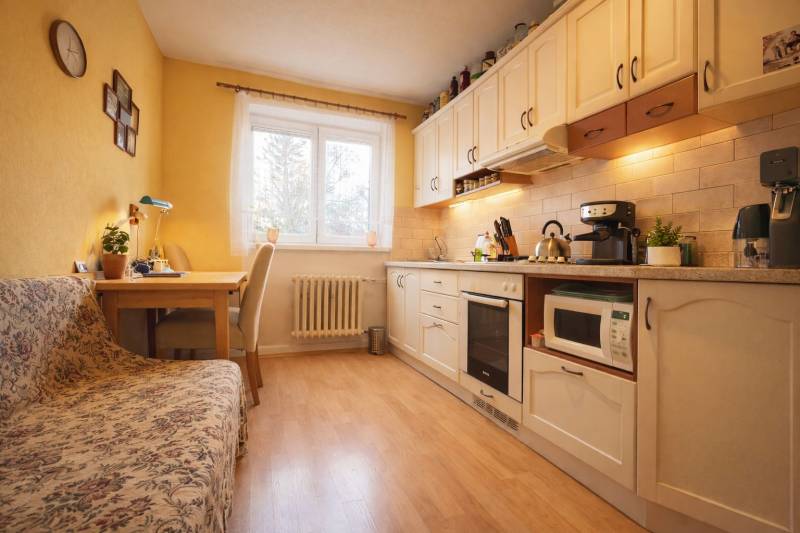 Küche in einer 2-Zimmer-Wohnung mit Holzboden, hellen Möbeln und einem Essbereich.