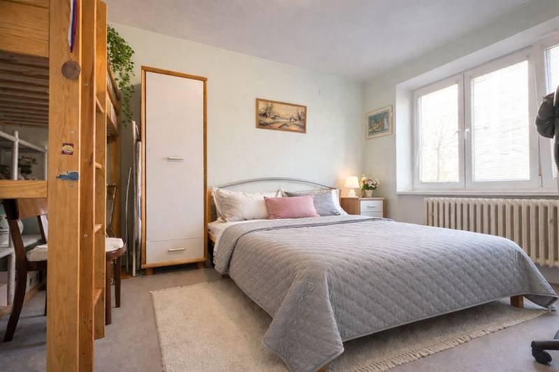 Schlafzimmer in einer 2-Zimmer-Wohnung mit großem Bett, Dekorationen und natürlicher Beleuchtung.