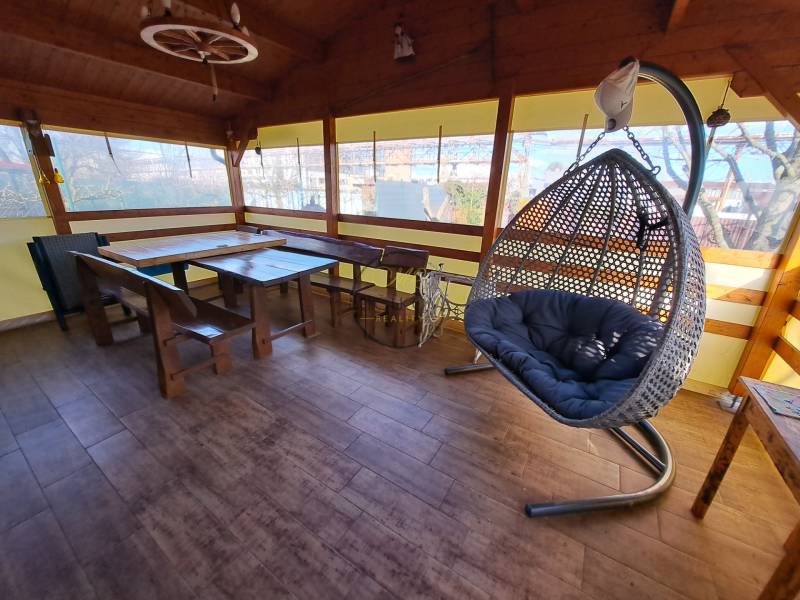 Eine Oase der Ruhe mit einem Hängesessel und Holzmöbeln auf einem Boden mit Holzdekor in den Gärten.